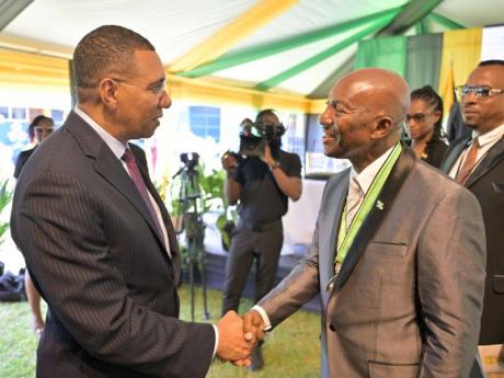 Prime Minister, Dr Andrew Holness (left), congratulates the newly installed Custos Rotulorum of Hanover, Lennox Anderson-Jackson, during the official installation ceremony held at Rusea's High School in Lucea on Thursday.