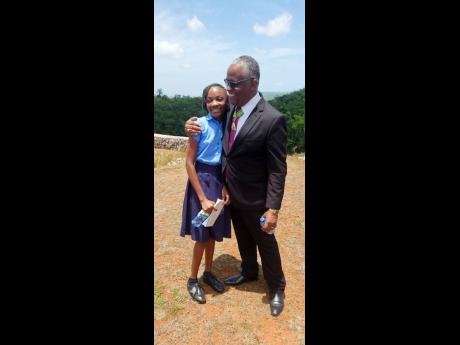 Credit: Glenda Anderson Custos of Manchester Garfield Green embraces Sanique Thompson, a student of the Old England Primary School.