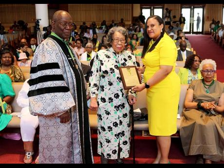 Jamaican Independence District of Columbia-Maryland-Virginia (DMV) 2024 Lifetime Achievement honouree, Carmen Edwards, receives her award from Lishann Salmon, deputy chief of Mission, Embassy of Jamaica. Looking on is Dr Bertram L. Melbourne, professor of 