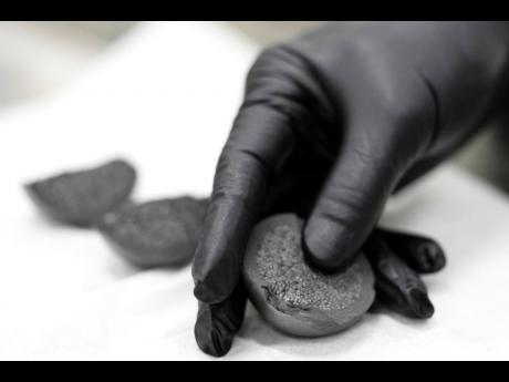 A laboratory worker holds a cross section of TRISO fuel, June 27, 2025, in Oak Ridge, Tennessee.