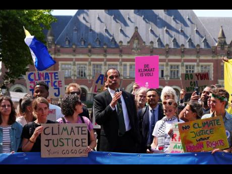 Ralph Regenvanu, Vanuatu’s minister for climate change, speaks surrounded by demonstrators as he arrives at the International Court of Justice in The Hague, Netherlands. 