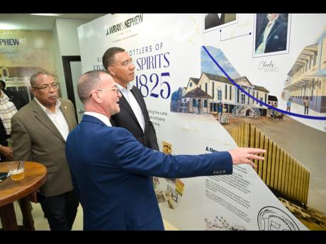 Prime Minister Dr Andrew Holness (right) listens as J. Wray and Nephew Limited Managing Director, Daniel Caron, highlights the company’s history during its 200th anniversary celebrations, held on July 23, at the entity’s corporate offices in New Kingst
