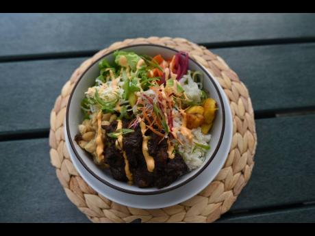Credit: Ian Allen Coconut rice, boneless oxtail, chopped lettuce, pickled carrots and cucumbers, fried plantain, broad beans, and coleslaw, served with a Scotch bonnet–tomato salsa and finished with an avocado crema.