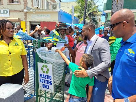 Montego Bay Mayor Richard Vernon (centre) looks on as residents of the western city deposit garbage into appropriately labelled garbage bins that were unveiled along Market Street in the vicinity of Sam Sharpe Square on Thursday. Also pictured are Aretha M