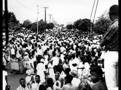 In this 1965 photo people are seen waiting in Seymour Place for the floats to form the central parade for the Grand Gala at the National Stadium.