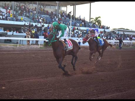 Credit: Anthony Minott/Freelance Photographer I DREAM AGAIN (left), ridden by Robert Halledeen, wins the 99th running of the Jamaica St Leger at Caymanas Park on July 6. At right is BURNING HEDGE (3) who placed third.