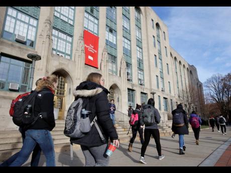 
In this 2018 photo students and passers-by carry book bags as they walk past an entrance to Boston University College of Arts and Sciences, in Boston. 