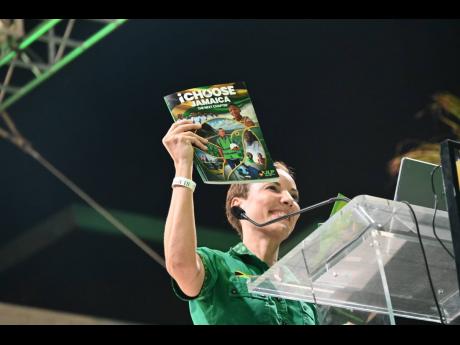 Kamina Johnson Smith holds up a copy of the Jamaica Labour Party's manifesto, launched last night during a mass rally in St James. 