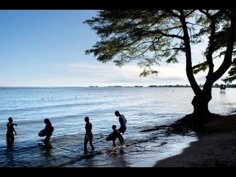 People wade into the waters of Lake Victoria, the world's second-largest freshwater lake, November 25, 2024, in Entebbe, Uganda. (AP Photo/David Goldman, File)