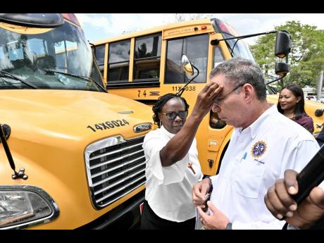 Bishop The Reverend Christine Gooden-Benguche, president of Jamaica Council of Churches, blesses the chool buses and Daryl Vaz, minister of science, energy, telecommunications and transport.
