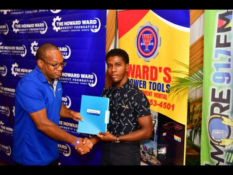 Renaldo Messam (right), a final-year nursing student at the University of Technology Jamaica, collects his Howard Ward Benefit Foundation Scholarship commitment documents from Dr Alpha Obika, chairman of the foundation’s scholarship committee. 
