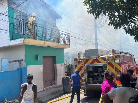 Credit: Andre Williams photo Firefighters attempt to put out a blaze in Maxfield Avenue area of St Andrew, yesterday.