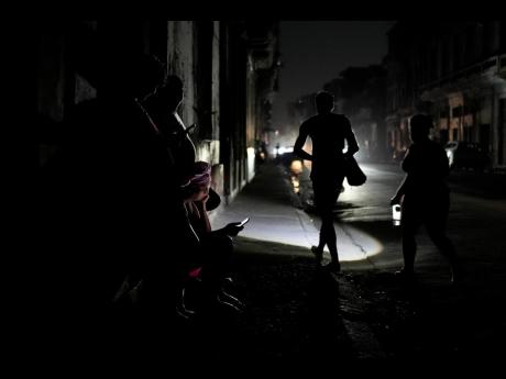 Residents walk on a street during a general blackout in Havana, Cuba, Friday, March 14, 2025. (AP Photo/Ramon Espinosa)