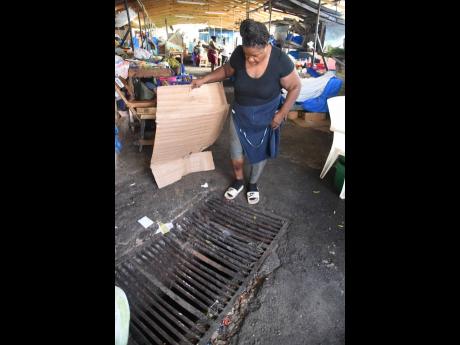 Market vendor Dorey McPherson shows the yet-to-be-repaired drain in which she injured her leg inside the Morant Bay Market last December.