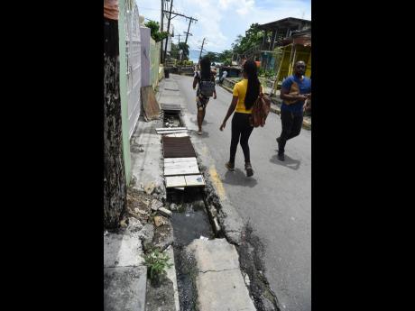 Pedestrians were forced to walk in the streets along Rosemary Lane in Morant Bay, St Thomas, last week because of missing drain covers.