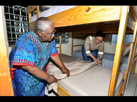 Annie Dawson Children’s Home founder Ivaline Nickie gets assistance in making the bed in one of the girls’ dormitories from Timara Jackson, who has been an avid supporter of the home for the last two years. 