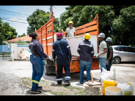 JPS Rockfort and Hunts Bay power station plant engineer, Timara Jackson (left), looks on as the moving team comprising (from second left) JPS instrument technician Colin Stone; power station maintenance man Arthur Chambers; Jeffrey Quarrie & Associates dri