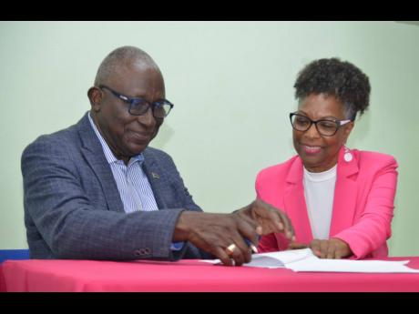 Major Retired Effiom Whyte. chairman of the Marcus Garvey in Schools Foundation, and Professor Rosalea Hamilton, chief executive officer, Lasco Chin Foundation, signing an agreement last Monday.