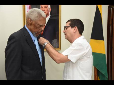 Cuban Ambassador Fermín Quiñones pins Errald Miller, husband of former Pime Minister Portia Simpson Miller, with the Cuban Medal of Friendship, one of Cuba’s highest honours for foreign leaders who have supported the country.