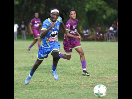 Credit: Ashley Anguin Cedric Titus High’s Terron Eccleston (left) dribbles away from William Knibb Memorial High’s Jaheem Brown (right) during their Zone D match in the ISSA daCosta Cup at William Knibb’s playing field yesterday. Ecclestion scored twice in his team’s 2-