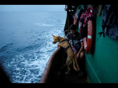 Venezuelan Abraham Castro rides a cargo vessel with other Venezuelan migrants through the Gulf of Panama as he, his partner and her two sons travel south after giving up on reaching the United States, Wednesday, Sept. 17, 2025. (AP Photo/Matias Delacroix)