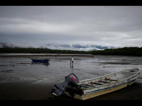 Venezuelan Abraham Castro and his partner's son Mathias Gomez walk on the beach in Jaque on Panama's Pacific coast, from where they will keep moving south toward Colombia, Friday, Sept. 19, 2025. Castro, his partner, and her two sons are returning home aft
