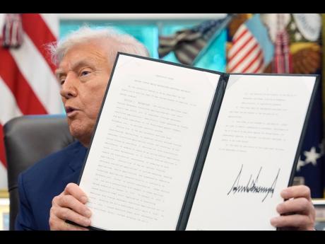 President Donald Trump holds a signed executive order regarding TikTok in the Oval Office at the White House, Thursday, September 25, 2025, in Washington. (AP Photo/Alex Brandon)