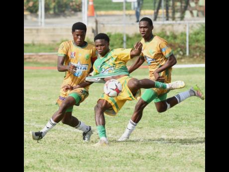 Excelsior High School’s Kimarly Scott (centre) has his shirt tugged by St Jago’s Jordon Taylor while attempting to kick during their ISSA/WATA Manning Cup football Game at the Courtney Walsh Oval yesterday. That game ended 0-0.
