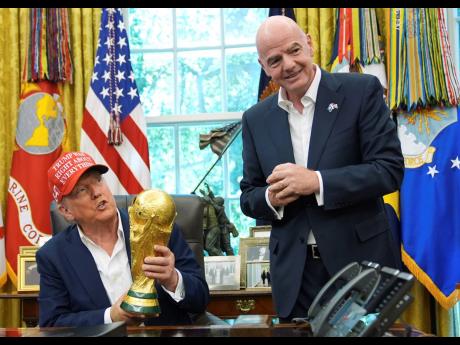 President Donald Trump holds the FIFA World Cup Winners Trophy as FIFA President Gianni Infantino looks on during an announcement in the Oval Office of the White House, August 22, 2025, in Washington. (AP Photo/Jacquelyn Martin, File)