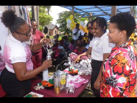 Special needs coordinator at the Ministry of Education, Skills, Youth and Information, Nicolette Thompson (right), and children’s officer at the Child Protection and Family Services Agency (CPFSA), Jesanya Scale-Menzies (centre), observe as caregiver fro