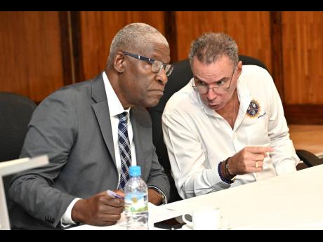Credit: Rudolph Brown/Photographer Daryl Vaz (right), minister of energy, transport and telecommunications, speaks with Owen Ellington, managing director of the Jamaica Urban Transit Company, during a briefing held yesterday to provide an update on the National Rural School Bus Programme at