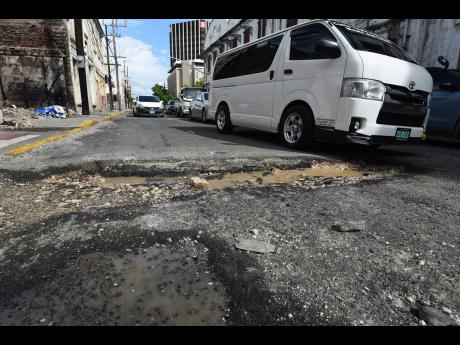 Credit: Ian Allen/Photographer A large pothole stretches across Harbour Street in downtown Kingston, forcing motorists to abandon two of the three lanes to avoid falling in. The pothole has been there for more than six months and has got wider during recent rains.