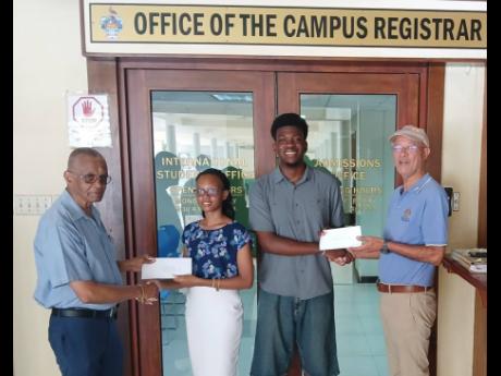 Radley Reid (left) and Donald Patterson (right), directors of the Rotary Club of St Andrew North Education Foundation, present education grants to Lilly Anne Douglas and Victor Stewart of The University of the West Indies. The recipients were two of four s