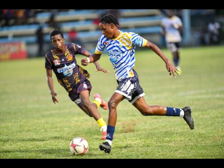 Jamaica College’s Malique Bucknor (right) drives the ball forward while being chased by St Andrew Technical High School’s Shankeno Grant during their ISSA/WATA Manning Cup clash at the Drewsland Stadium on September 27.