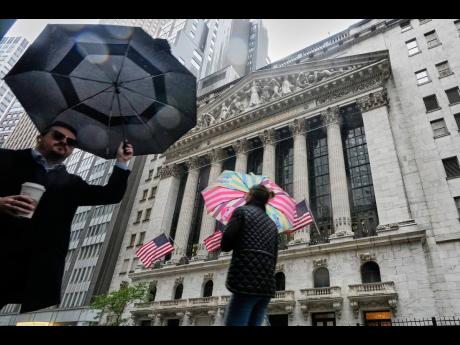 
People with umbrellas pass the New York Stock Exchange on Monday, October 13, 2025.