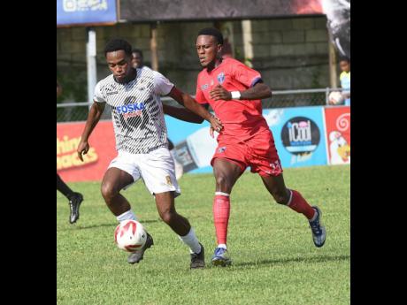 Adrian Reid (left) of  Cavalier dribbles clear of Diamond Clarke of Spanish Town Police FC during their Jamaica Premier League match at the Waterhouse Mini Stadium yesterday.