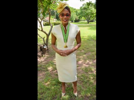 Veteran journalist Emily Shields, newly conferred with the Order of Distinction in the Commander class, completes a classic look with a gold fascinator.