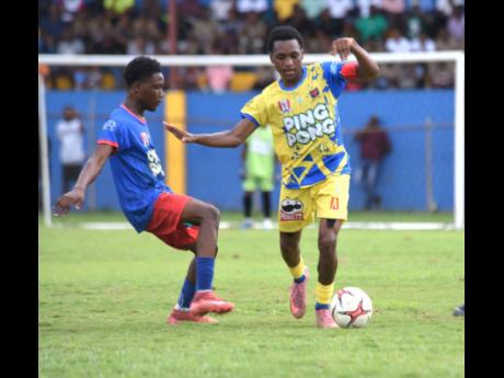 St Elizabeth Technical High School’s (STETHS) Deandre Barnett (right) tries to evade the challenge of Kemps Hill High School’s Rcardo Dea during their ISSA daCosta Cup round-of-16-clash at the STETHS Sports Complex yesterday.