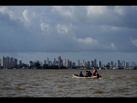 Credit: AP A boat sails on the bay of the Guama River with Belém, Brazil, in the background.
