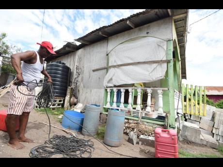 Cleon Banton prepares rope to tie down the roof of his house in Compound, Alligator Pond, Manchester, last Friday as Hurricane Melissa approaches.