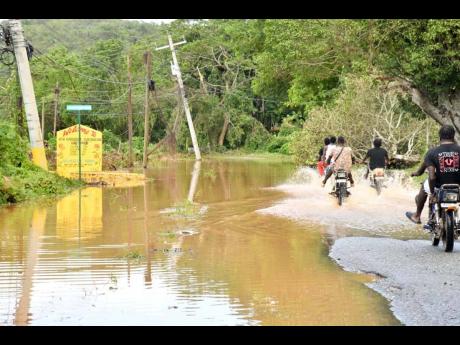 Residents of Big Pond, Old Harbour traverse a main road in the area following Hurricane Melissa on Wednesday.