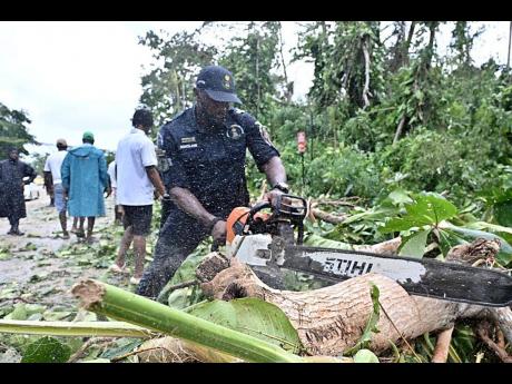 Corporal Dwain Sinclair of the Specialised Operations team, part of a 16-member crew, clearing fallen trees from the Ocho Rios main road after Hurricane Melissa.