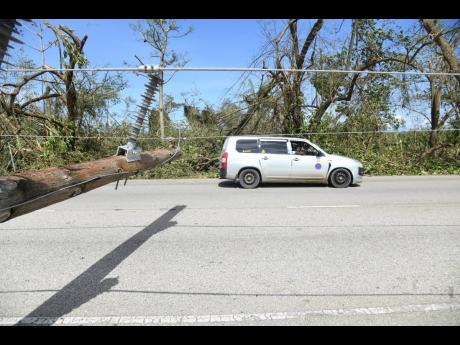 Motorists drive past a downed light pole along the St Ann’s Bay main road in St Ann, following the passage of Hurricane Melissa on Wednesday.