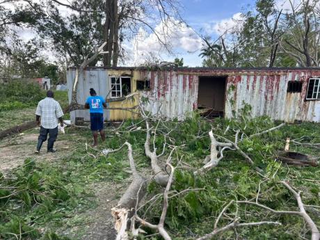 Residents of Little Haiti in Negril, Westmoreland at the scene where a homeless man who lived under a container was crushed during the passage Hurricane Melissa.