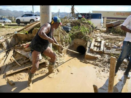 Rose Holness clears mud from her property in Catherine Hall, St James. 