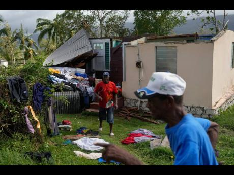Residents dry belongings at a house damaged by Hurricane Melissa in Santa Cruz.