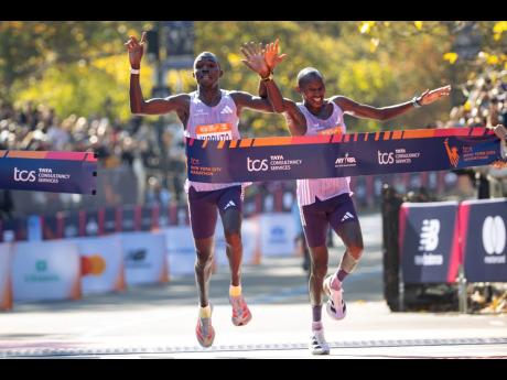 Benson Kipruto (left) and Alexander Mutiso cross the finish line to win first and second place, respectively, in the men’s elite division of the New York City Marathon yesterday in New York. 