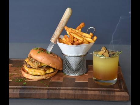 The featured storm breaker burger, served with fries, stood proudly in the good company of this smoky Amber elixir cocktail.