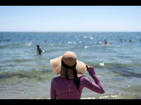Ruth Wilson, who has lupus and is sensitive to the sun, stands at the water’s edge while at the beach with family in August in South Yarmouth, Massachusetts.