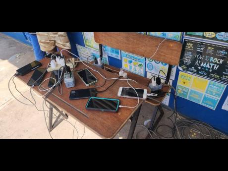 Residents of the Lacovia Primary School shelter in St Elizabeth charge their phones using power supplied by the RG CARES outreach team; providing critical connectivity after the widespread devastation and dislocation caused by Hurricane Melissa.
